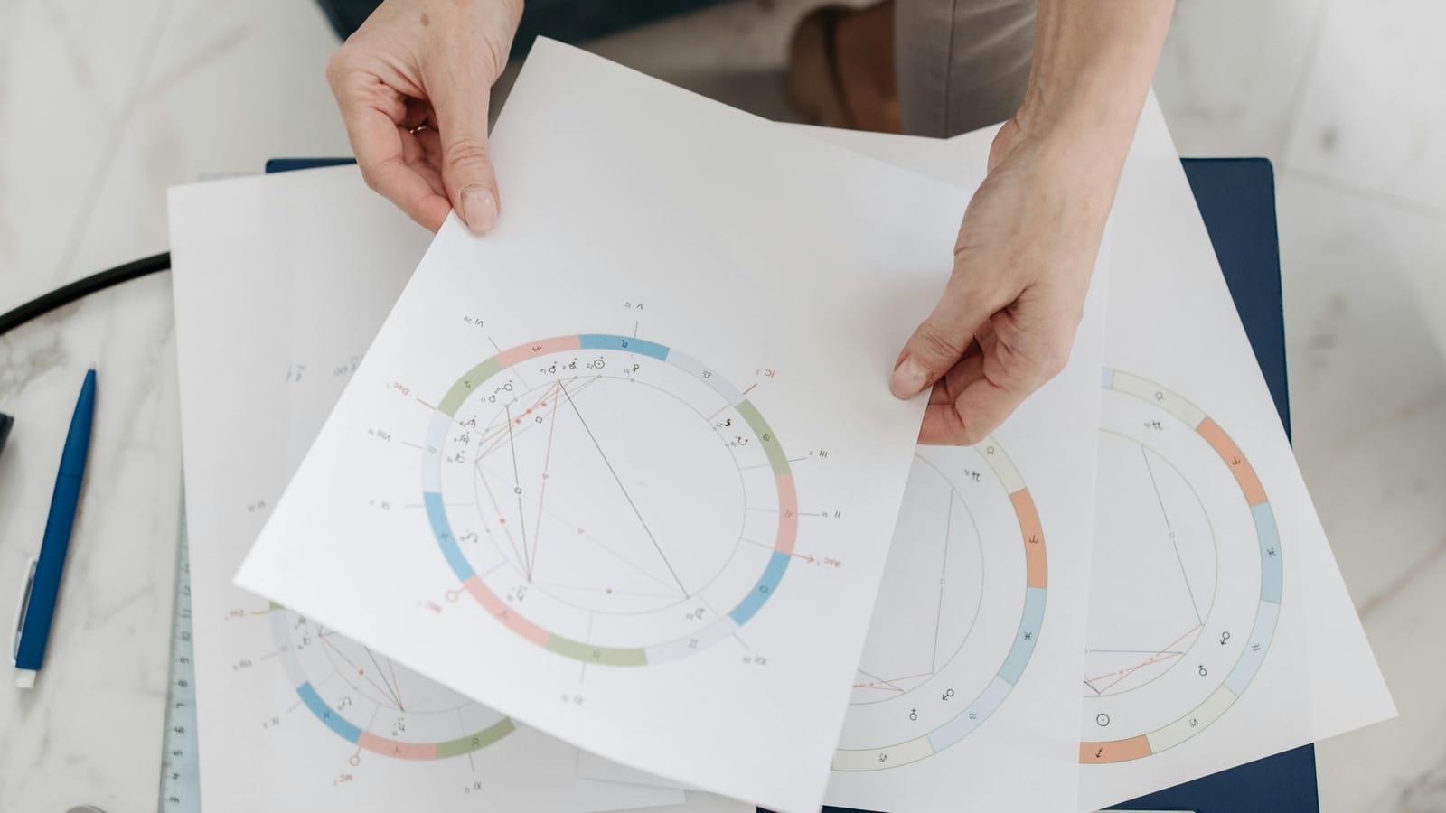 Hands holding astrological charts and graphs, symbolizing horoscopes and fortune-telling.