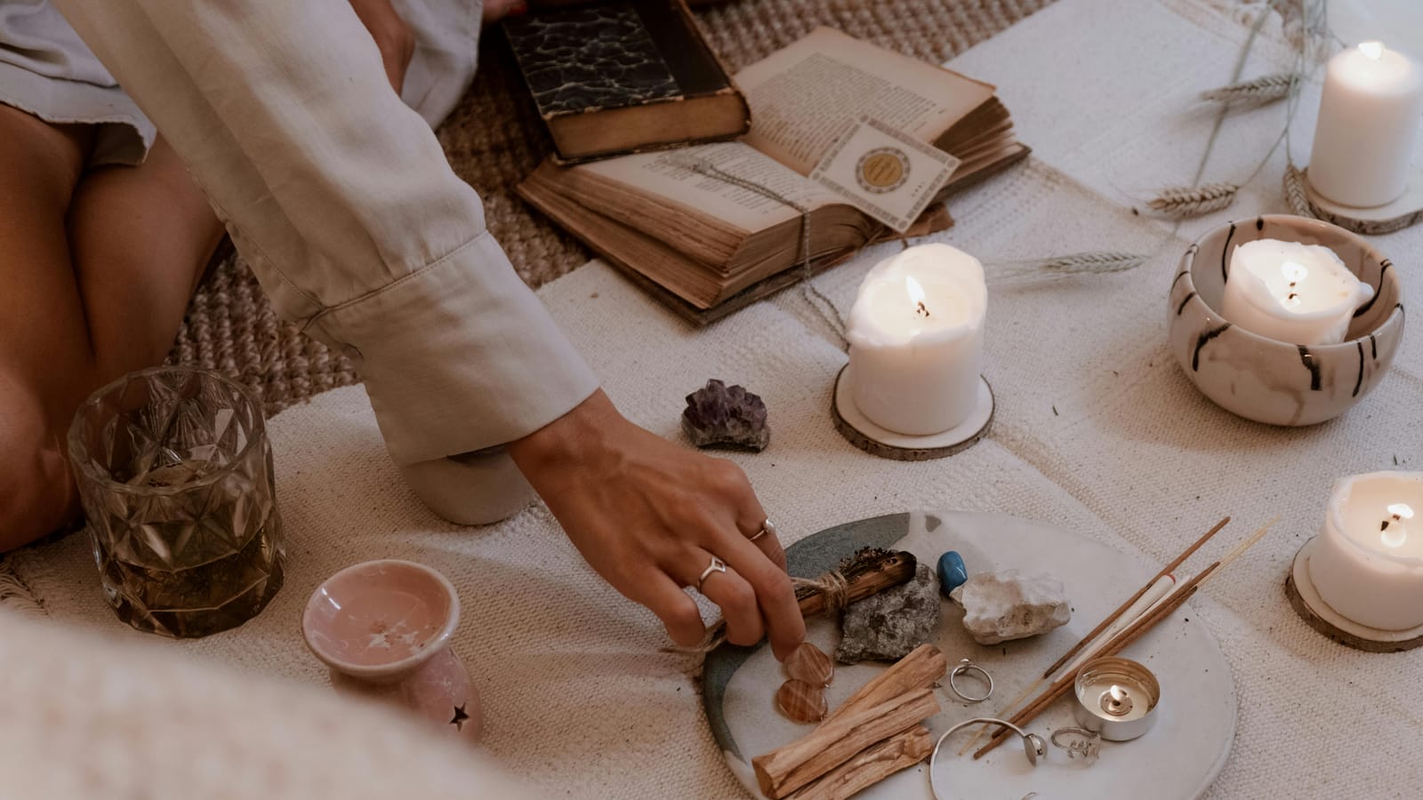 A peaceful ritual scene with candles, crystals, and incense sticks on a wooden table.